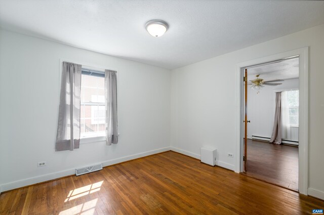 unfurnished room featuring baseboards, visible vents, a ceiling fan, and wood finished floors