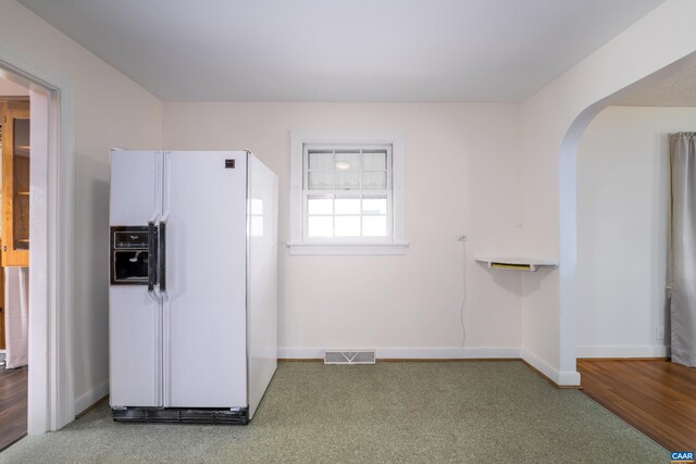 kitchen featuring visible vents, carpet floors, arched walkways, white refrigerator with ice dispenser, and baseboards