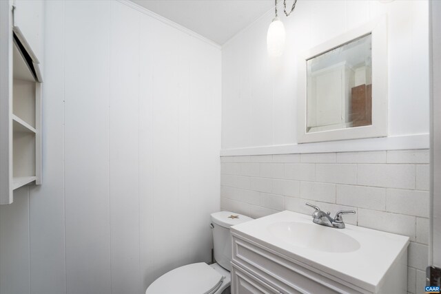 half bathroom featuring vanity, toilet, backsplash, and tile walls