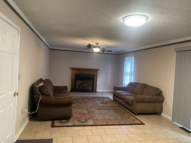 living area with baseboards, a fireplace with flush hearth, ceiling fan, and a textured ceiling