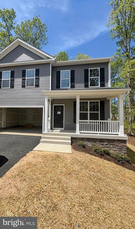 split level home with an attached garage, driveway, and covered porch