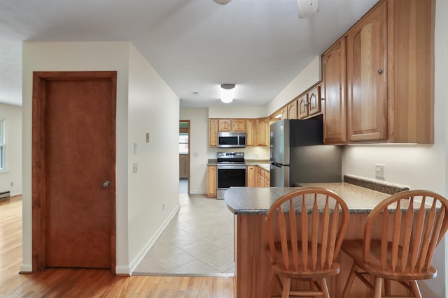 3423 Smith Creek Rd, New Market, VA 22844 - kitchen with appliances with stainless steel finishes, a peninsula, baseboards, a kitchen bar, and light wood-style floors