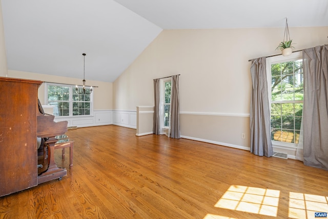 2777 Peppervine Ct, Charlottesville, VA 22911 - unfurnished living room with a chandelier, vaulted ceiling, light wood-type flooring, and wainscoting