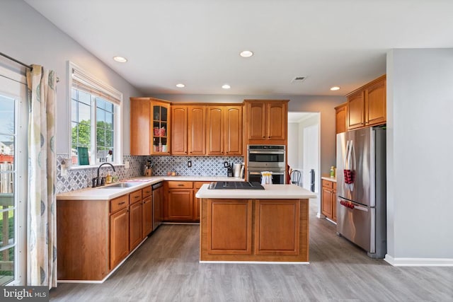 kitchen with appliances with stainless steel finishes, a center island, light countertops, light wood finished floors, and recessed lighting
