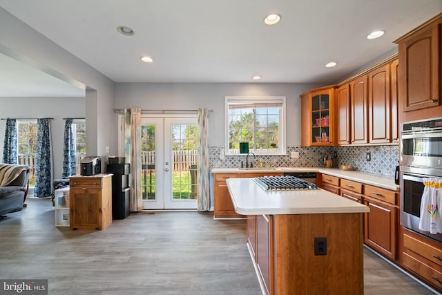 kitchen featuring light countertops, recessed lighting, a sink, stainless steel double oven, and decorative backsplash