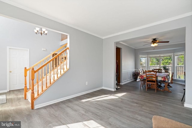 living room with wood finished floors, stairs, crown molding, a chandelier, and ceiling fan
