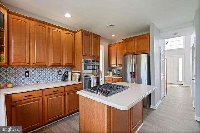kitchen featuring appliances with stainless steel finishes, light countertops, wood finished floors, and recessed lighting