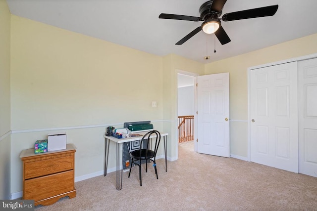 carpeted office space featuring a ceiling fan and baseboards