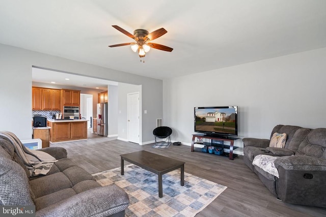 living area with wood finished floors, ceiling fan, baseboards, and recessed lighting