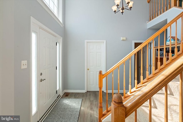 foyer entrance featuring a high ceiling, a chandelier, stairway, wood finished floors, and baseboards