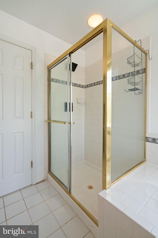bathroom with a shower stall and tile patterned floors
