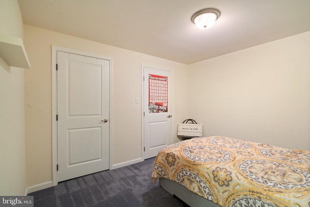 bedroom featuring dark carpet and baseboards