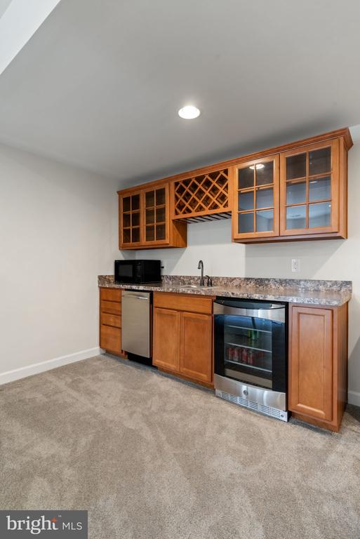 10430 Aspen Highlands Dr, Spotsylvania, VA 22553 - indoor wet bar featuring stainless steel dishwasher, black microwave, light colored carpet, baseboards, and recessed lighting