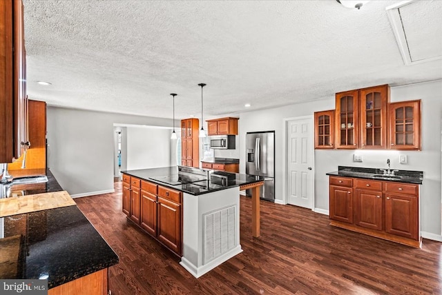 kitchen with appliances with stainless steel finishes, a sink, a textured ceiling, baseboards, and dark wood-type flooring