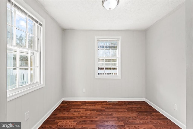 spare room with baseboards, dark wood-style flooring, and a textured ceiling
