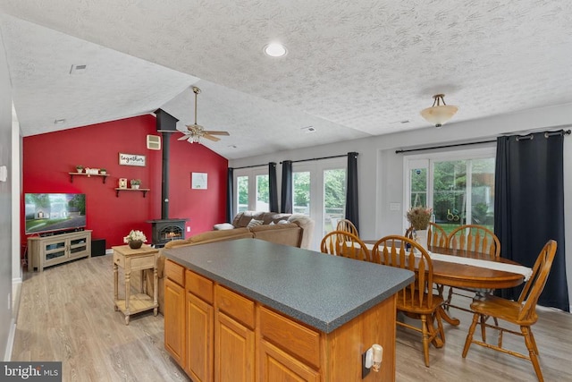 6701 Towles Mill Rd, Spotsylvania, VA 22551 - kitchen featuring a textured ceiling, light wood finished floors, ceiling fan, a wood stove, and a kitchen island
