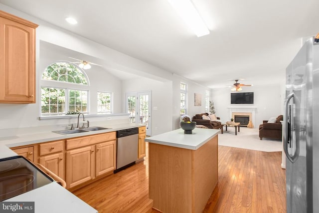 10911 Jarvis Ct, Fredericksburg, VA 22407 - kitchen featuring appliances with stainless steel finishes, ceiling fan, light wood-type flooring, a center island, and a glass covered fireplace