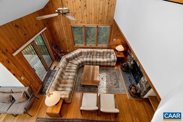living area with wood finished floors, wood walls, high vaulted ceiling, and a ceiling fan