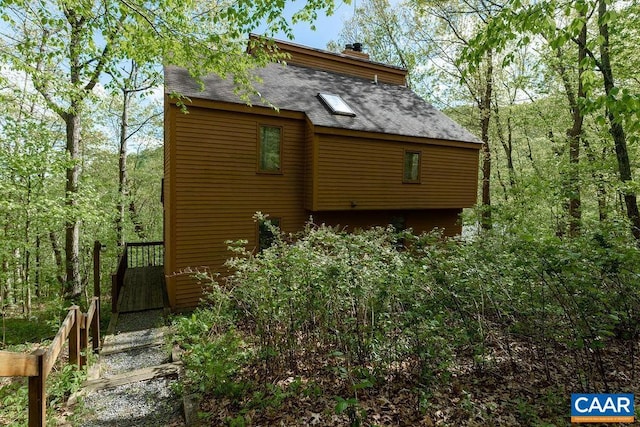 view of property exterior featuring roof with shingles and a chimney