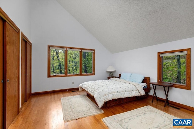 bedroom featuring baseboards, lofted ceiling, and light wood finished floors