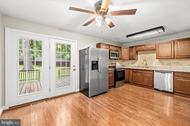 6908 Wild Turkey Dr, Spotsylvania, VA 22553 - kitchen with stainless steel appliances, light wood-type flooring, tasteful backsplash, brown cabinets, and a ceiling fan