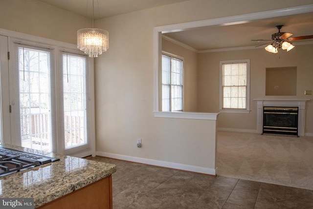 unfurnished dining area with baseboards, a ceiling fan, crown molding, a fireplace with flush hearth, and tile patterned floors