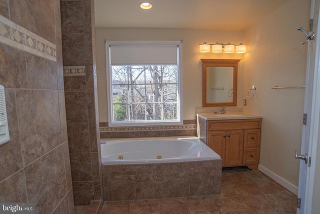 bathroom with a tub with jets, vanity, and recessed lighting