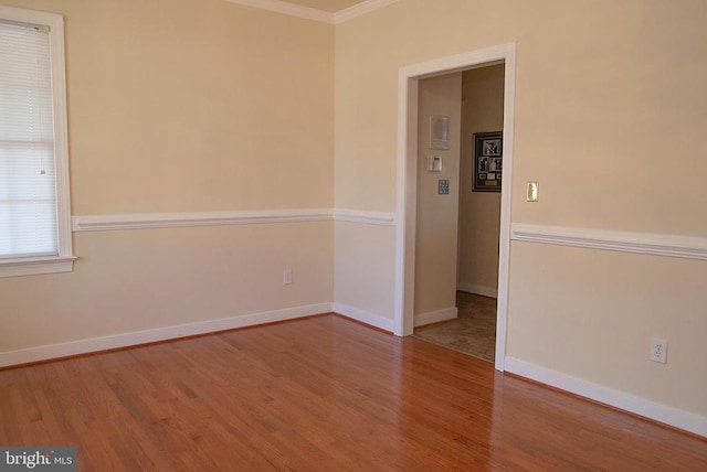 spare room featuring ornamental molding, wood finished floors, and baseboards