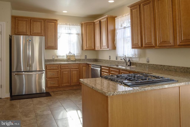 kitchen with stainless steel appliances, a sink, a peninsula, recessed lighting, and light stone counters