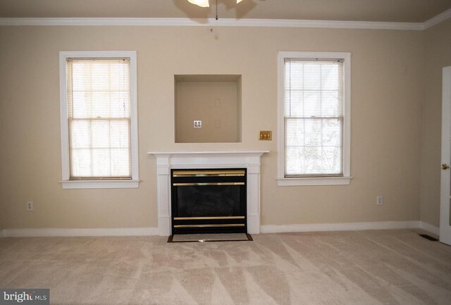 unfurnished living room with ornamental molding, a fireplace with flush hearth, carpet floors, healthy amount of natural light, and a ceiling fan