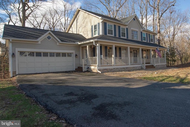 view of front of home featuring driveway, covered porch, and an attached garage