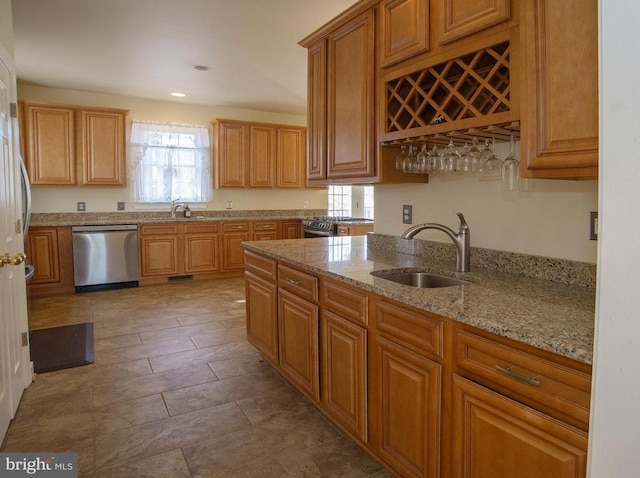 kitchen featuring dishwasher, a sink, light stone countertops, brown cabinets, and recessed lighting