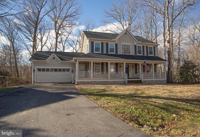 colonial house with driveway, covered porch, an attached garage, and a front yard