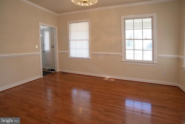 empty room featuring wood finished floors, baseboards, and ornamental molding