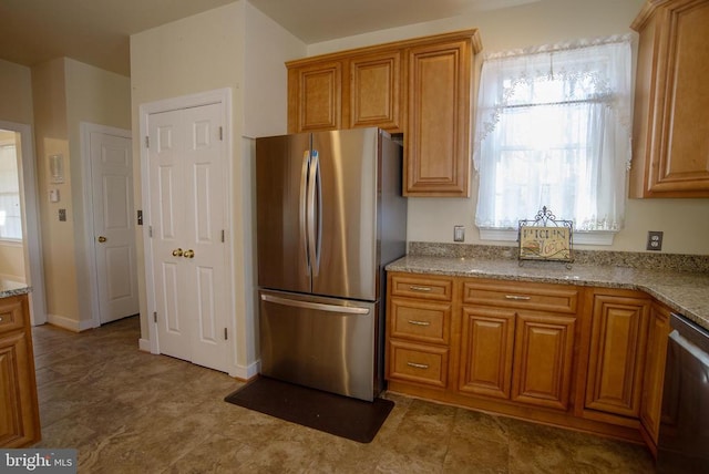 kitchen with appliances with stainless steel finishes, healthy amount of natural light, brown cabinets, and light stone counters