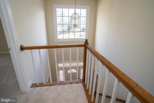 staircase featuring carpet and a chandelier