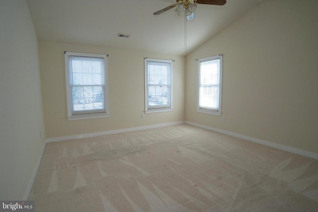 carpeted spare room featuring healthy amount of natural light, baseboards, ceiling fan, and vaulted ceiling