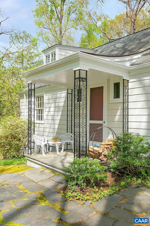 property entrance featuring a shingled roof and a porch