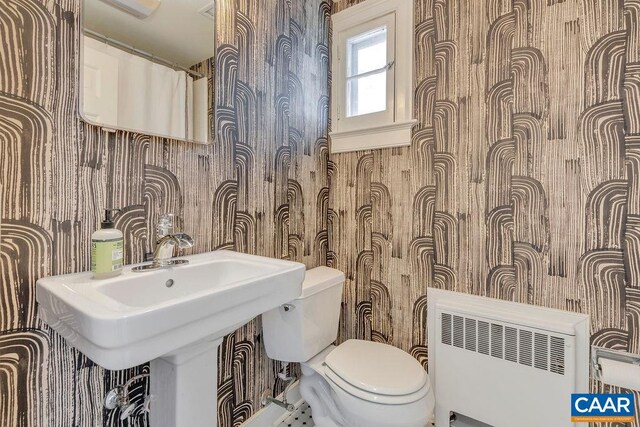 bathroom with radiator heating unit, toilet, and wallpapered walls