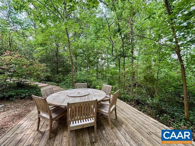 deck featuring outdoor dining space and a wooded view