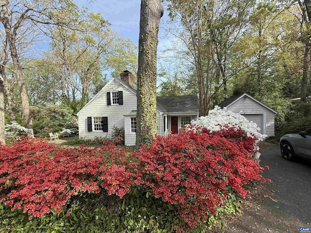 view of property exterior with a chimney, a detached garage, and an outdoor structure