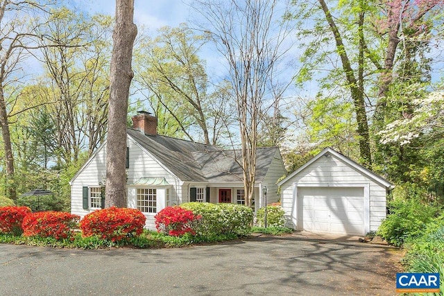 view of home's exterior featuring a chimney, a garage, and driveway