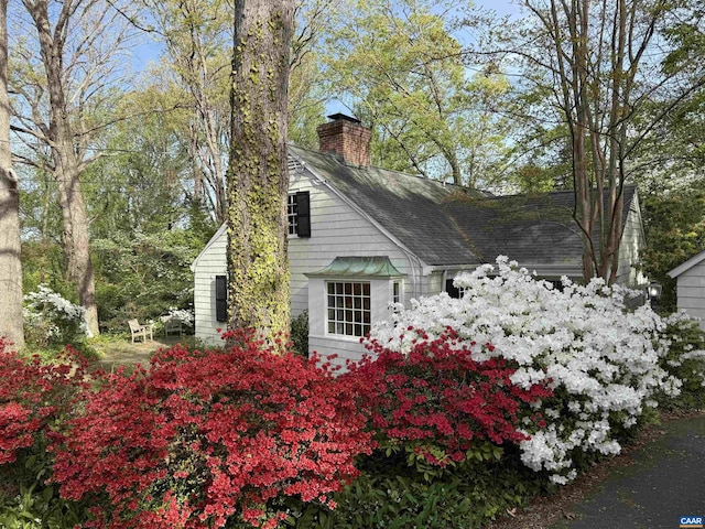 view of side of home featuring a chimney and roof with shingles