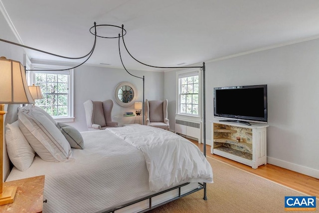 bedroom with radiator heating unit, ornamental molding, wood finished floors, and baseboards