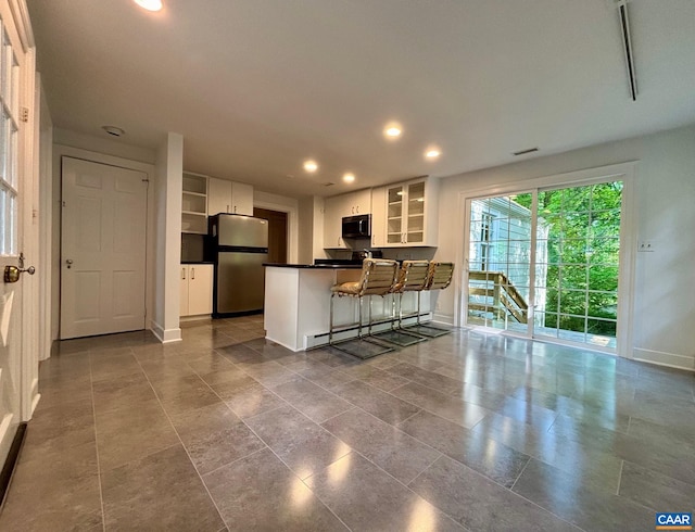 kitchen featuring freestanding refrigerator, black microwave, baseboards, dark countertops, and a peninsula