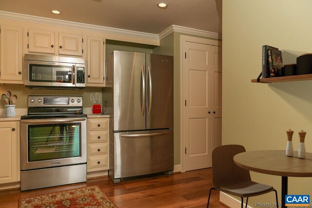 kitchen with appliances with stainless steel finishes, dark wood finished floors, recessed lighting, ornamental molding, and light countertops