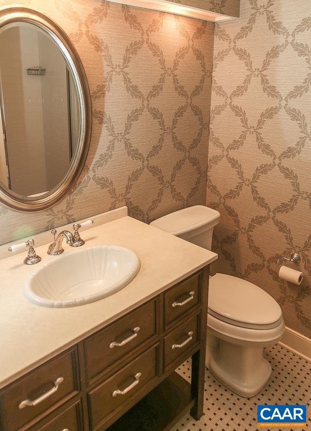half bath with vanity, toilet, and wallpapered walls