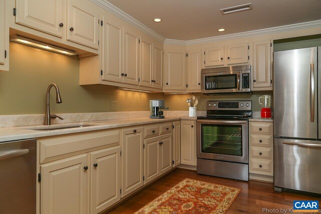 kitchen featuring stainless steel appliances, a sink, light countertops, dark wood-type flooring, and recessed lighting