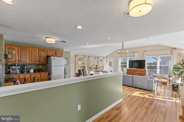 2266 Honeyville Rd, Stanley, VA 22851 - kitchen with freestanding refrigerator, brown cabinets, vaulted ceiling, light wood-style flooring, and a textured ceiling