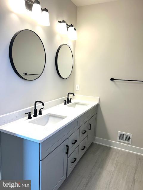 bathroom with double vanity and baseboards